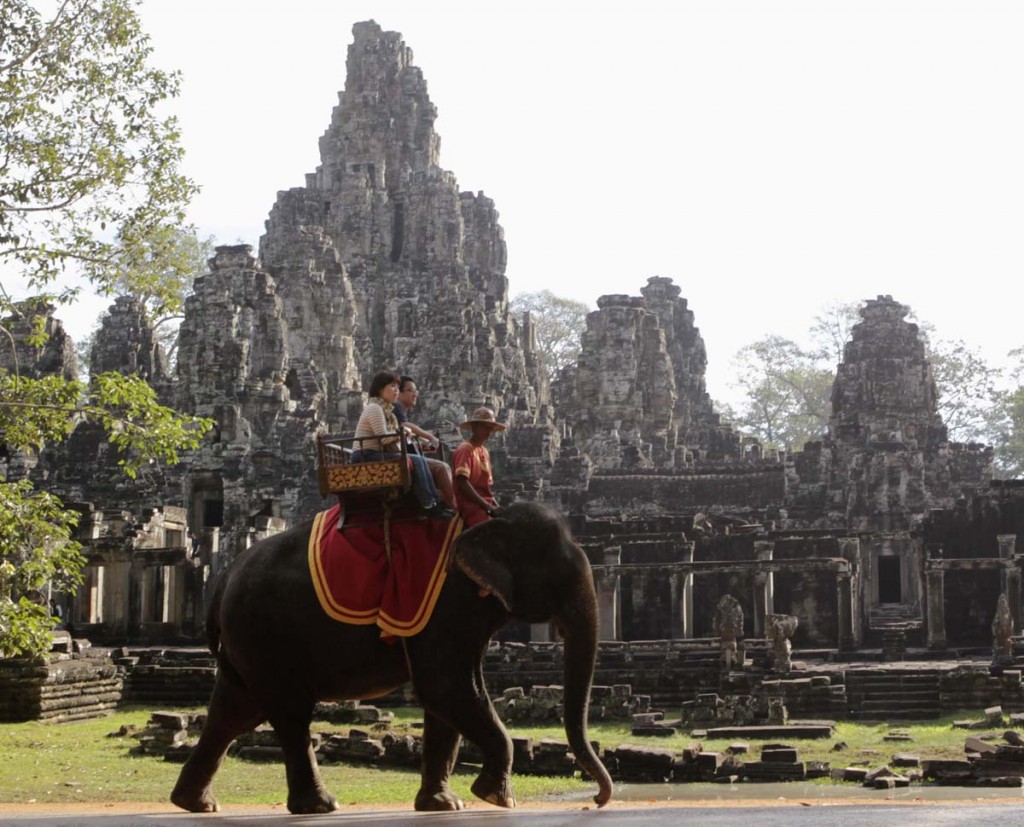 Tourists ride an elephant past the ruins of Cambodia's Bayon temple in Siem Reap