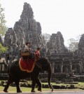 Tourists ride an elephant past the ruins of Cambodia's Bayon temple in Siem Reap