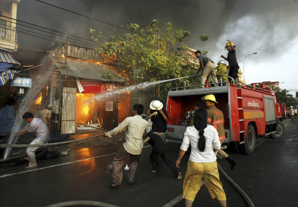 Firefighters and residents try to put out a fire that engulfed the neighbourhood in Phnom Penh